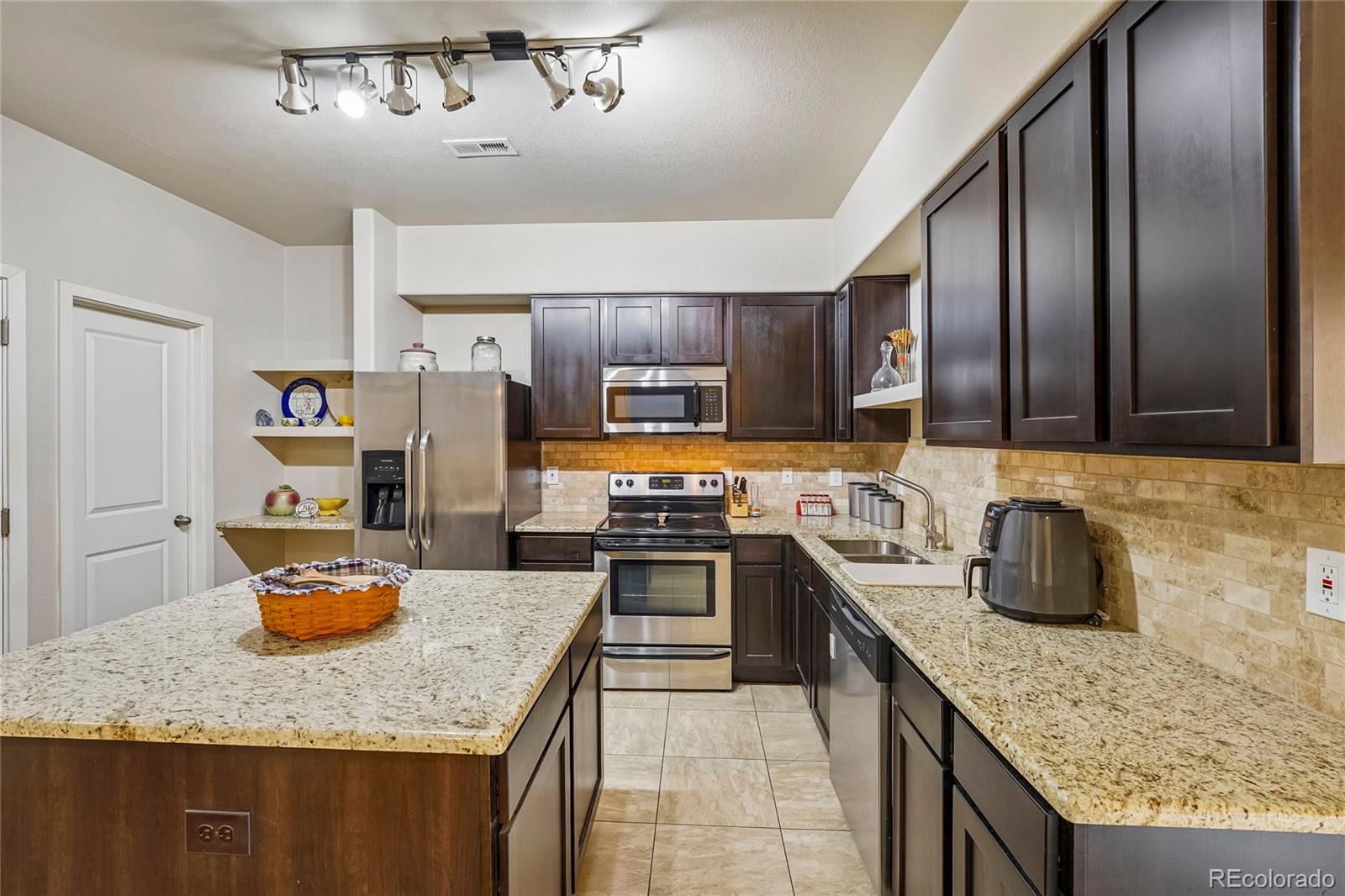 3611 South Perth Circle, Unit 102 Aurora, CO 80013 - Photo 10 of 40 a kitchen with stainless steel appliances granite countertop a sink stove and refrigerator