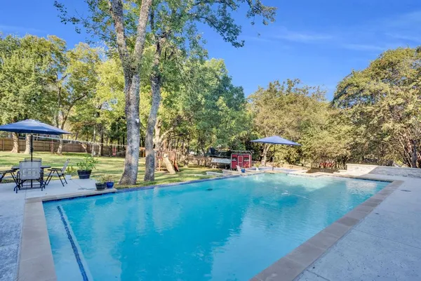 a view of a swimming pool with lawn chairs under an umbrella