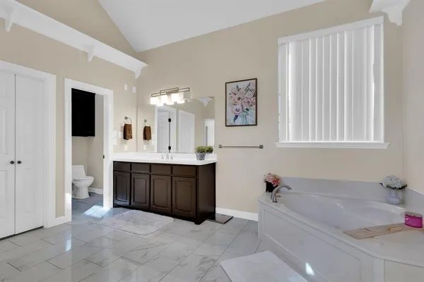 a spacious bathroom with a tub sink and mirror