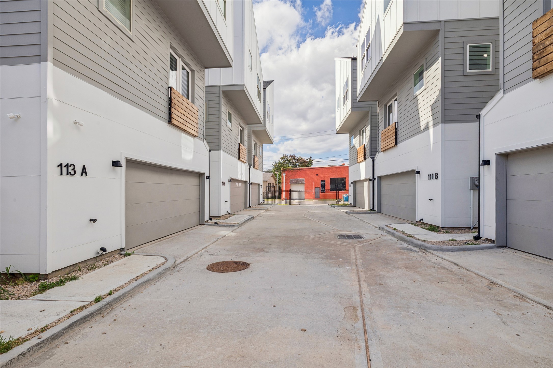 111 Milby Street Houston, TX 77003 - Photo 2 of 39 Modern townhouse complex with multiple units featuring two-car garages and contemporary siding. The area is clean and well-maintained, with a concrete driveway leading to the units. The architecture is sleek and urban, offering a sense of community in a compact space.