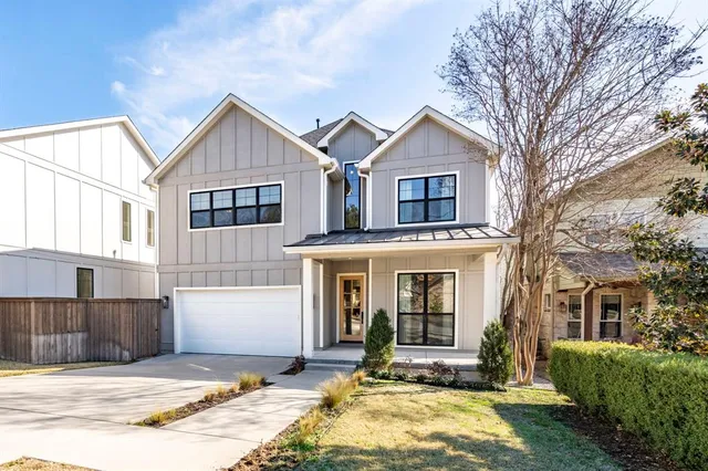 a view of a brick house with a large windows and a yard with plants and large trees