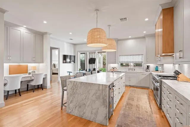 a large kitchen with stainless steel appliances lots of counter space windows and a chandelier