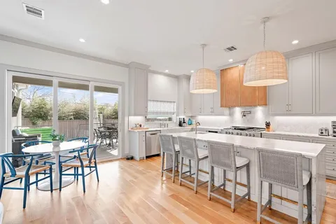 a kitchen with stainless steel appliances granite countertop dining table chairs stove and white cabinets
