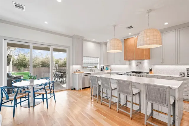 a kitchen with stainless steel appliances granite countertop dining table chairs stove and white cabinets