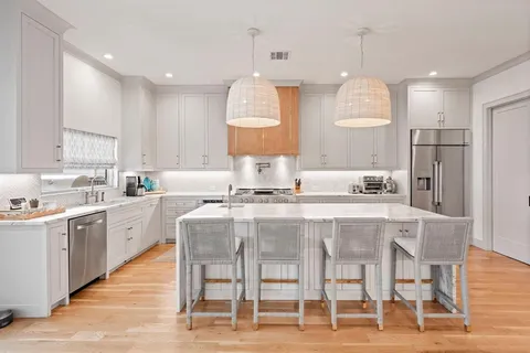 a kitchen with stainless steel appliances kitchen island granite countertop a kitchen island and chairs in it