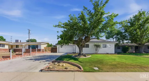 a front view of a house with a garden and tree