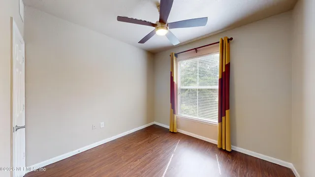 a view of an empty room with wooden floor and a window