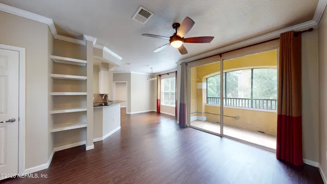 a view of an empty room with a window and wooden floor