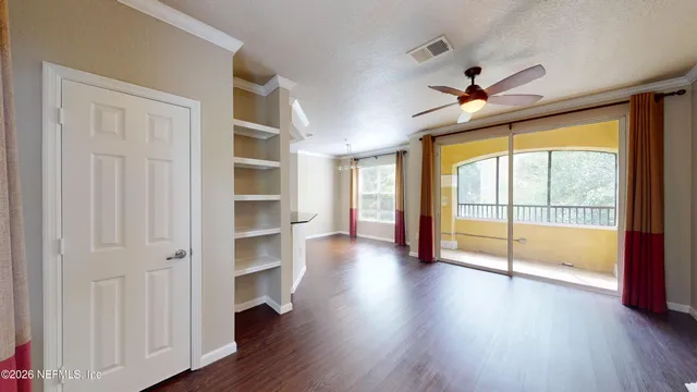 a view of an empty room with a window and wooden floor