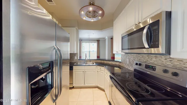 a kitchen with stainless steel appliances granite countertop a sink a stove a microwave and wooden cabinets