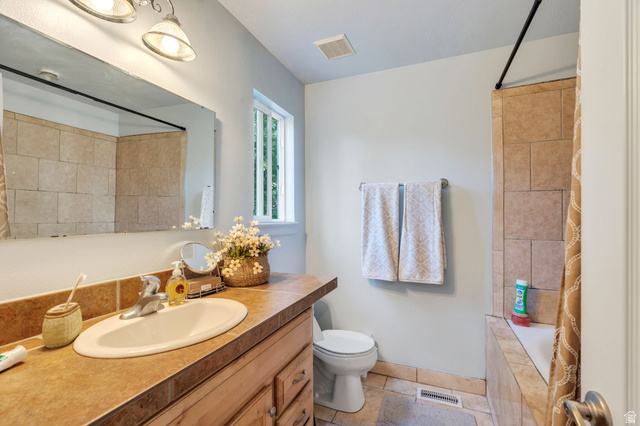 1727 South Sandhill Road Orem, UT 84058 - Photo 12 of 27 Bathroom featuring a wood-finish vanity with an oval undermount sink, a tiled countertop, and a large wall-mounted mirror
