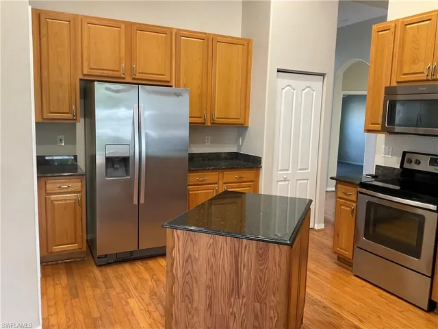 a kitchen with stainless steel appliances granite countertop a refrigerator a stove and a sink with wooden floor