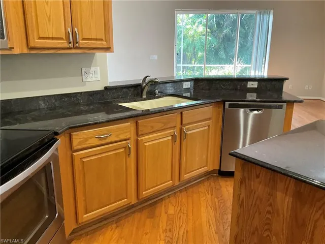 a kitchen with granite countertop cabinets stainless steel appliances a sink and window