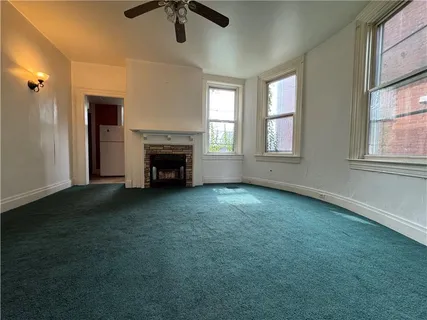 an empty room with fireplace fan and windows