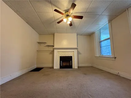 an empty room with chandelier fan and windows
