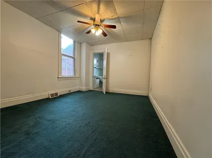 an empty room with windows and fan