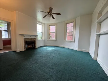 an empty room with windows and fireplace