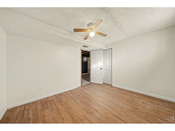 a view of an empty room and cabinet with a ceiling fan
