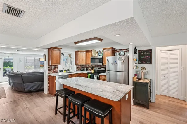 a kitchen with stainless steel appliances granite countertop a table chairs and a refrigerator
