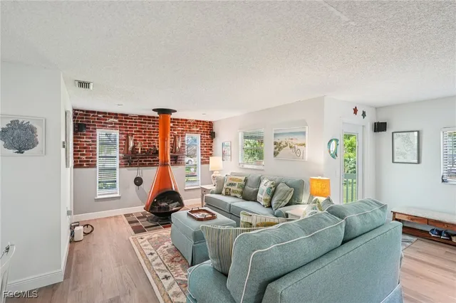 a living room with furniture two large window and a wooden floor