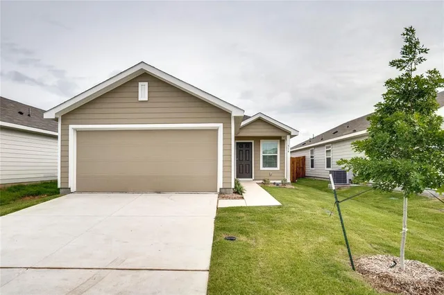 a front view of house with yard and trees in the background