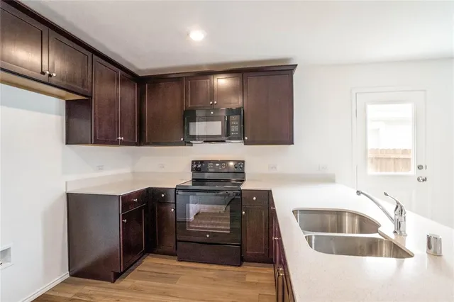 a kitchen with stainless steel appliances granite countertop a sink dishwasher stove and oven with wooden floor