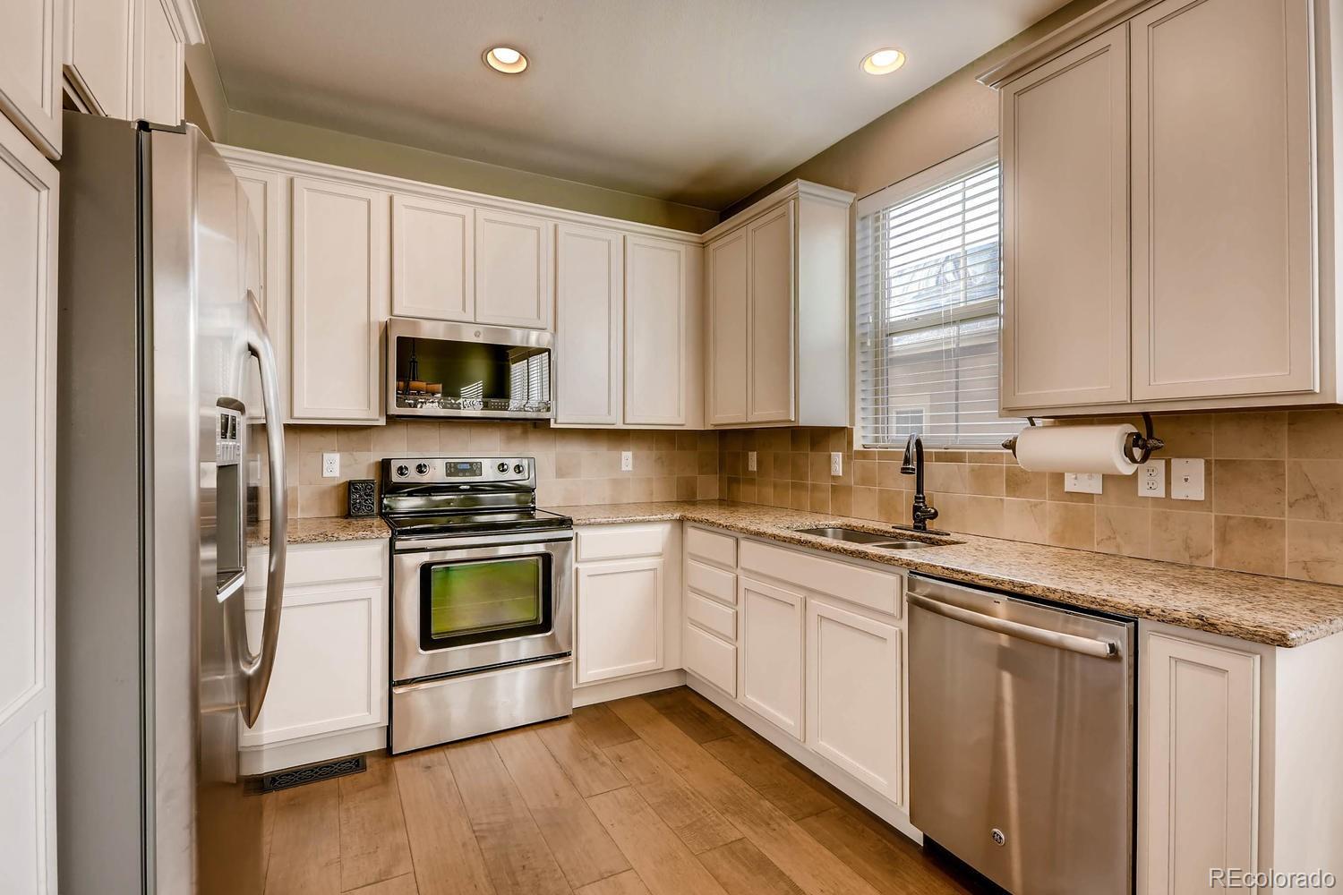 10261 Bellwether Lane Lone Tree, CO 80124 - Photo 2 of 35 a kitchen with stainless steel appliances granite countertop a stove a sink and a microwave