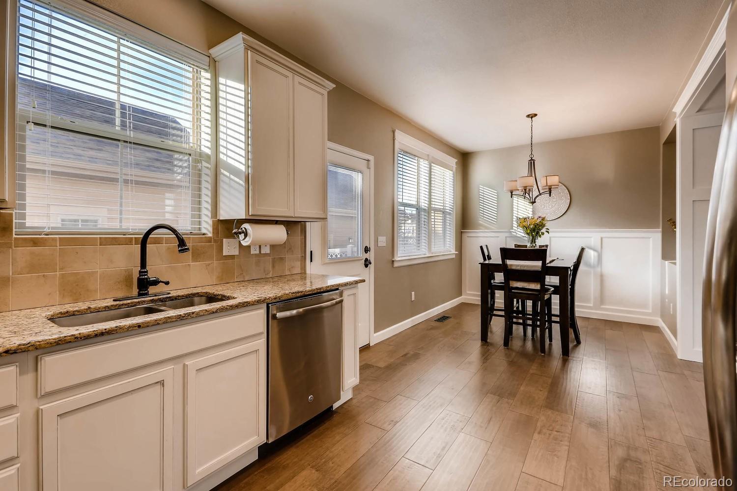 10261 Bellwether Lane Lone Tree, CO 80124 - Photo 4 of 35 a kitchen with stainless steel appliances granite countertop a sink a stove a dining table and chairs