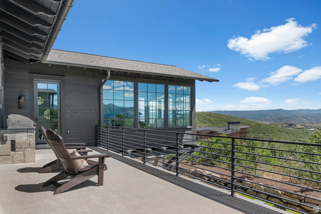 2192 East Outlaw Road Kamas, UT 84036 - Photo 33 of 80 Exterior deck with a stone-clad built-in grill station, multiple windows, and a metal railing