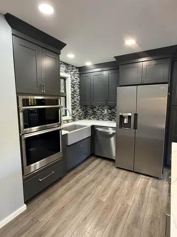 a kitchen with a refrigerator stainless steel appliances wooden floor washer and dryer