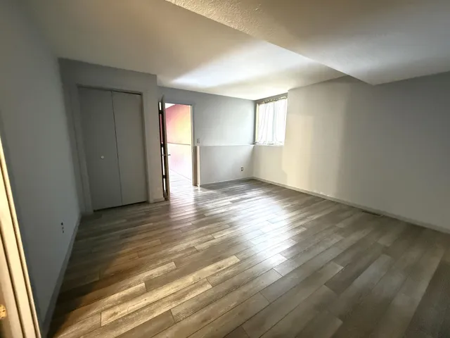 an empty room with wooden floor and windows