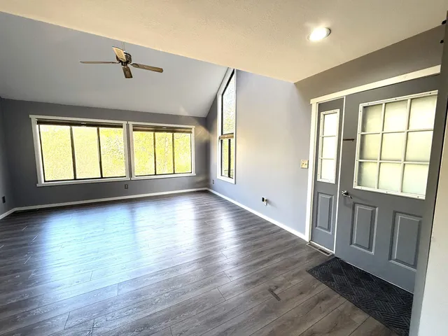 an empty room with wooden floor and windows