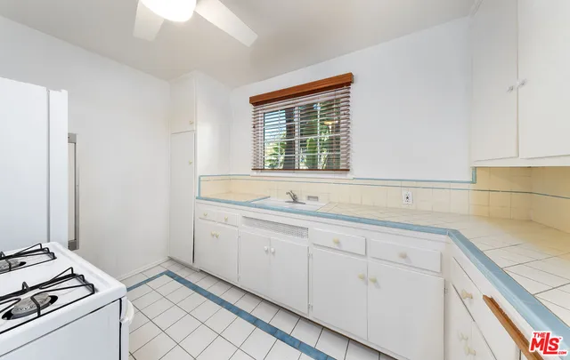 a view of cabinets a sink and a stove in a kitchen