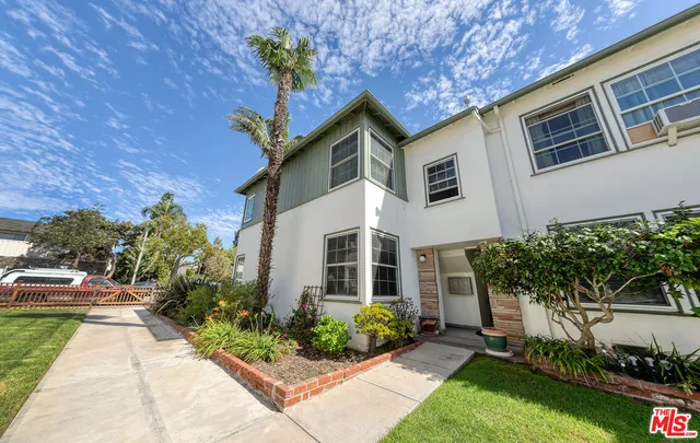 a front view of a house with a yard and potted plants