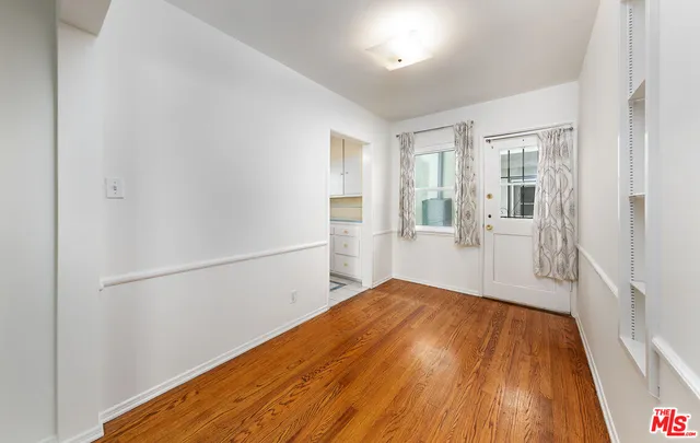 a view of a big room with wooden floor and windows