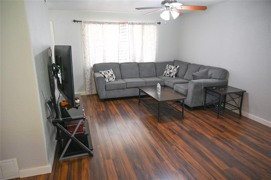 1352 Simpson Drive Hurst, TX 76053 - Photo 24 of 40 Spacious living area featuring wood-finish flooring, light grey walls, and a ceiling fan with integrated lighting