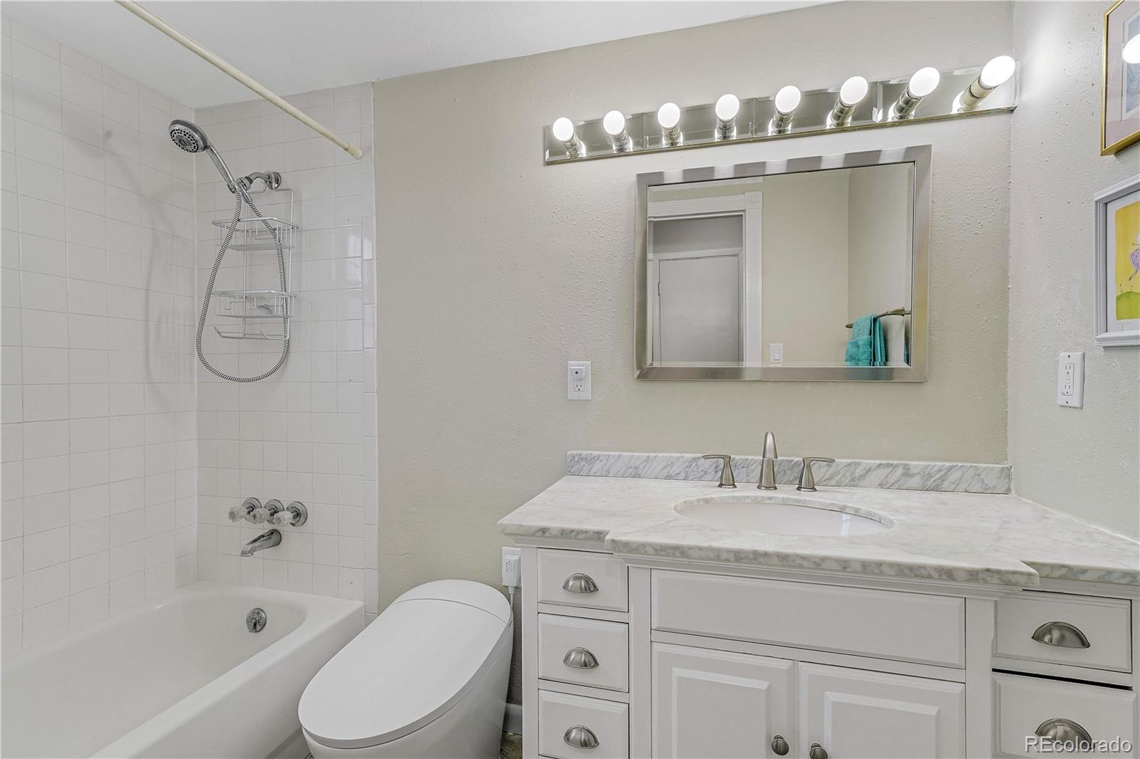 3855 South Monaco Street, Unit 203 Denver, CO 80237 - Photo 13 of 26 a bathroom with a granite countertop sink a toilet and a bathtub