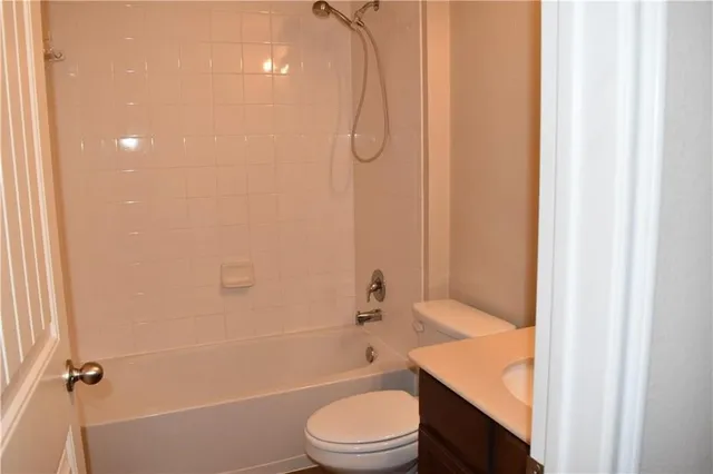 a bathroom with a granite countertop bathtub shower sink vanity and toilet