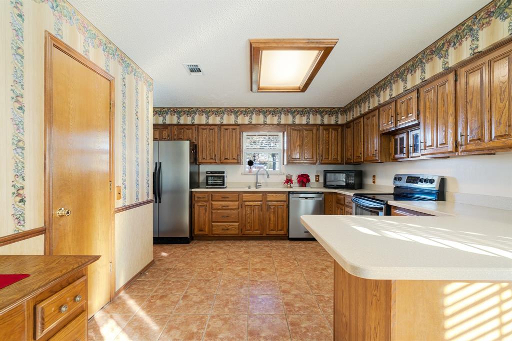 925 Medalist Street Paris, TX 75460 - Photo 8 of 24 a kitchen with stainless steel appliances a refrigerator and a stove top oven