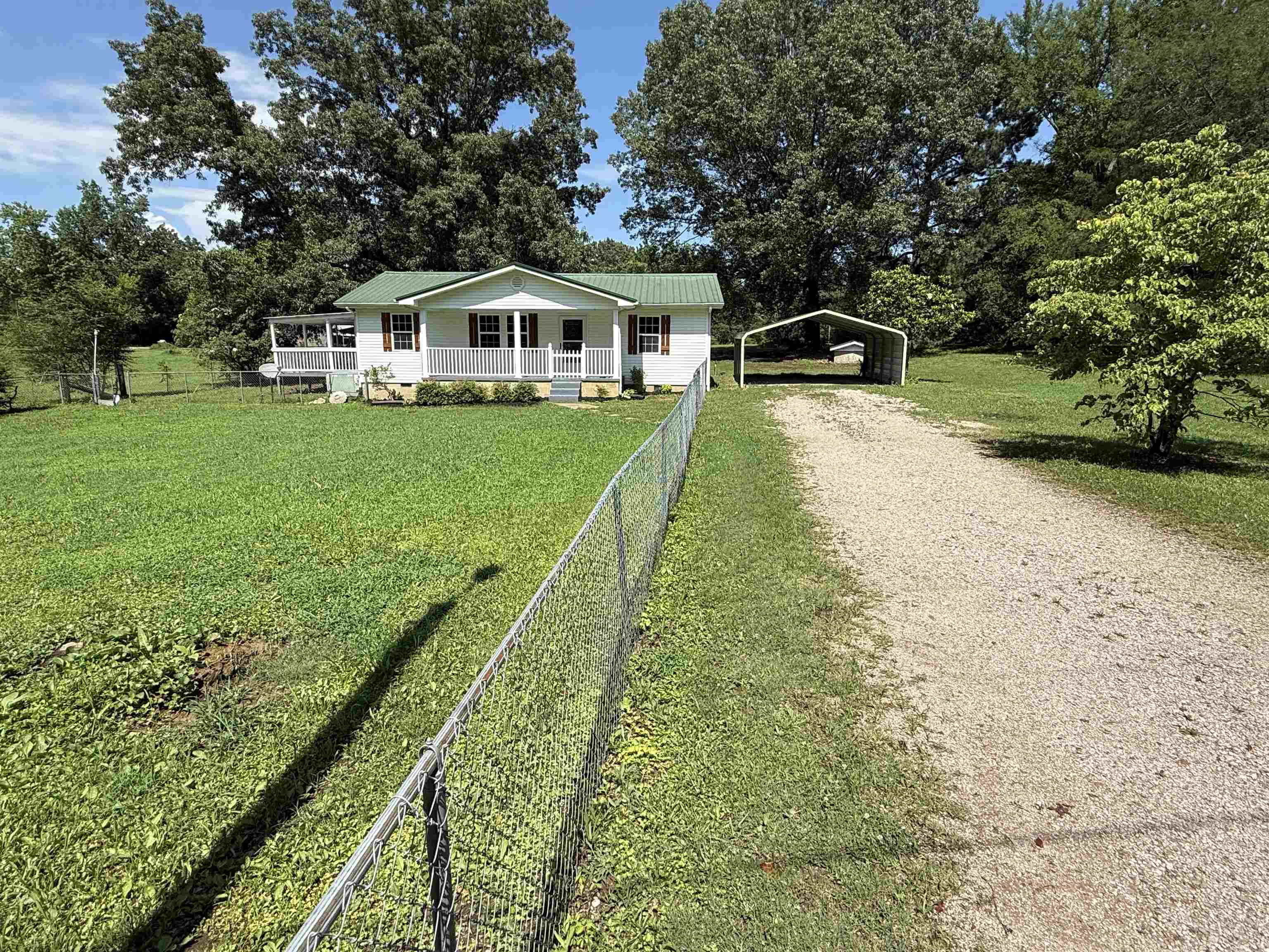 1390 Caney Branch Road Adamsville, TN 38310 - Photo 3 of 37 View of front of property featuring dirt driveway, a porch, a detached carport, and a metal roof
