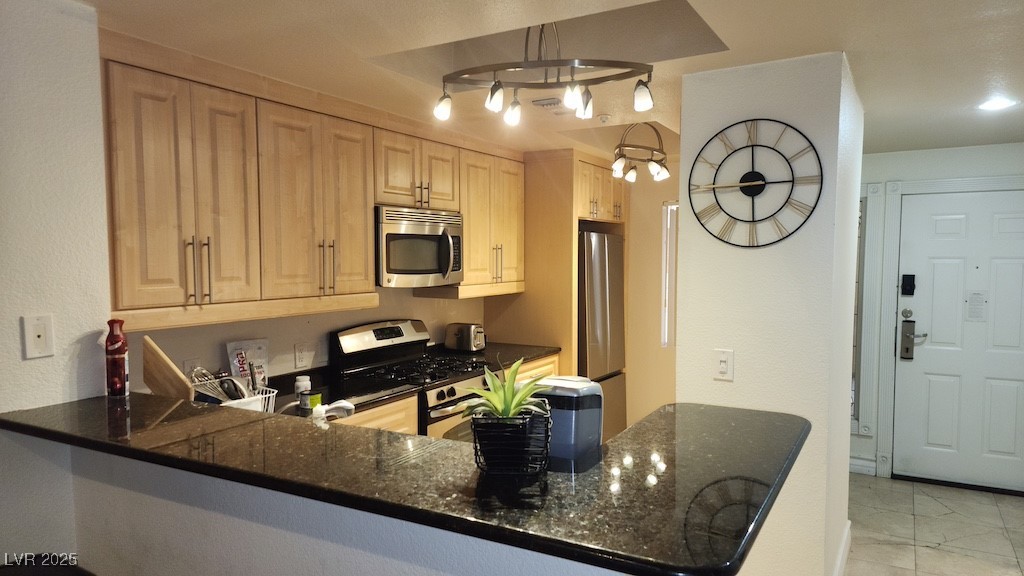 270 East Flamingo Road, Unit 133 Las Vegas, NV 89169 - Photo 2 of 13 Kitchen featuring appliances with stainless steel finishes, a peninsula, dark stone countertops, and light brown cabinetry