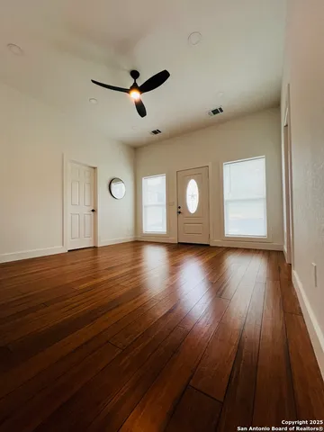 an empty room with wooden floor and windows
