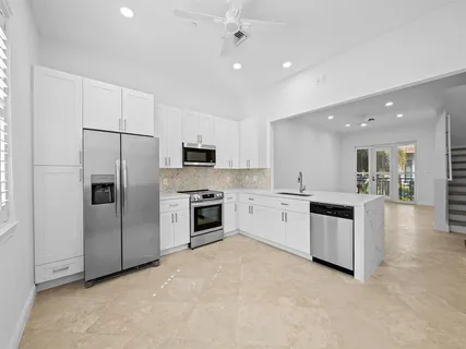 a large white kitchen with a refrigerator a stove top oven a sink and dishwasher