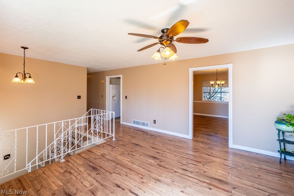 3601 River Road Vienna, WV 26105 - Photo 7 of 40 Empty room featuring suspended lighting, light wood-style flooring, and a ceiling fan