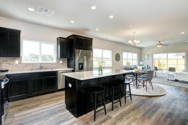 a kitchen with stainless steel appliances granite countertop a table chairs sink and cabinets