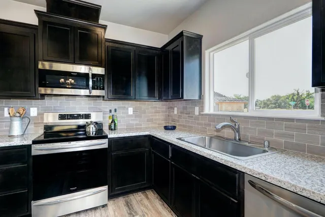 a kitchen with stainless steel appliances a sink stove and microwave
