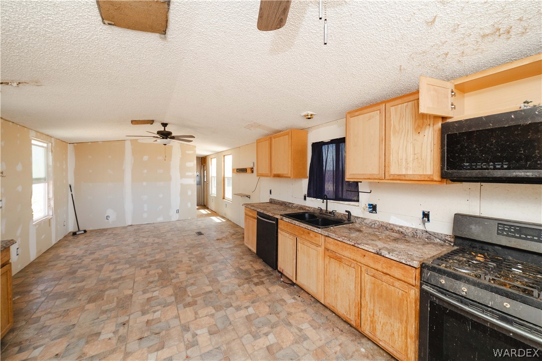 16435 South Wyatt Earp Road Yucca, AZ 86438 - Photo 8 of 57 Kitchen area featuring light wood-finish cabinetry, a black stovetop range, and a built-in microwave