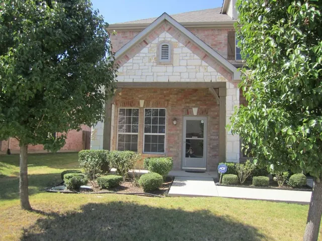 a front view of a house with a yard and potted plants