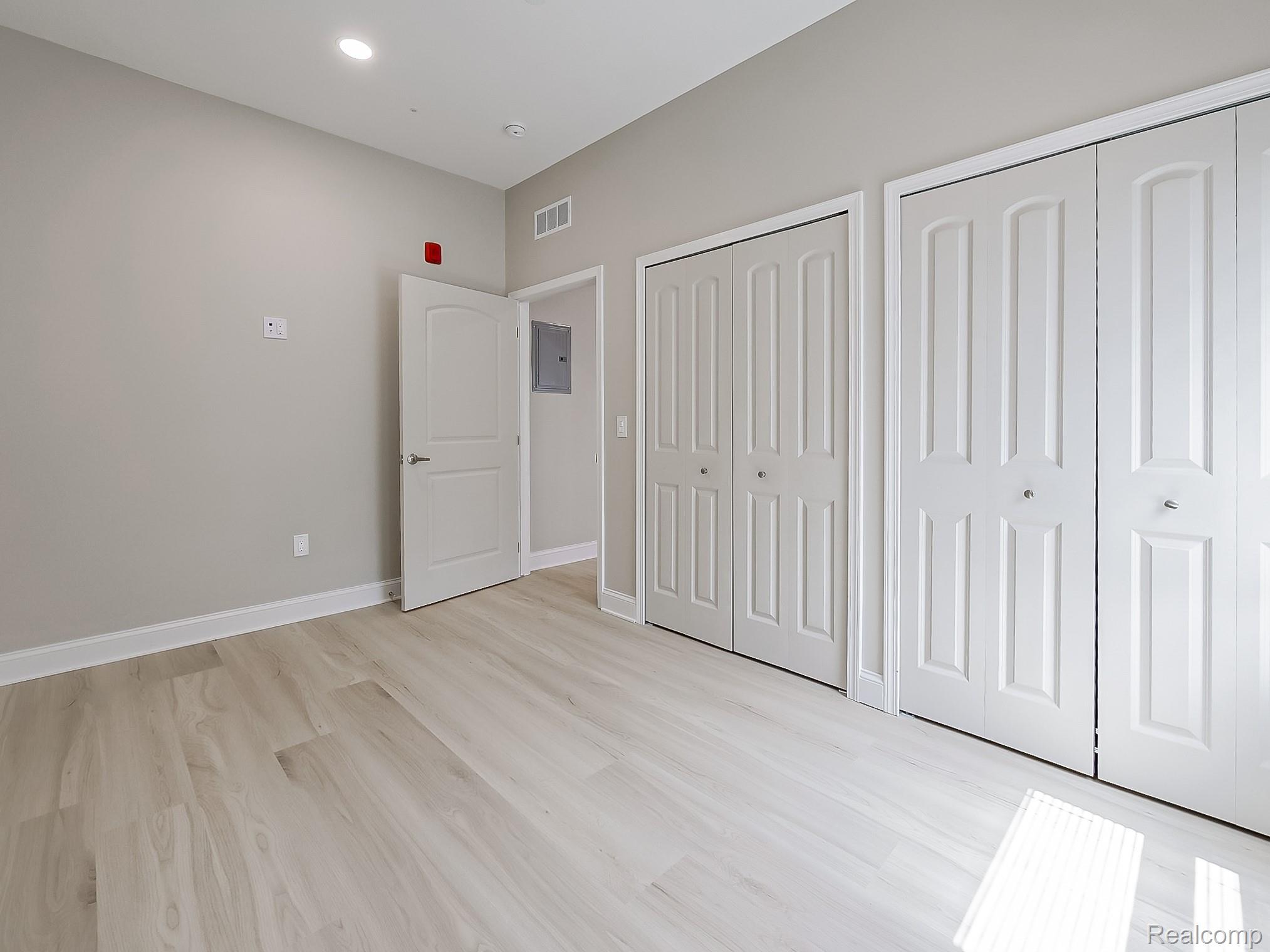 31480 Warren Road, Unit 101 Westland, MI 48185 - Photo 8 of 26 Unfurnished bedroom with two closets, light wood finished floors, recessed lighting, and electric panel