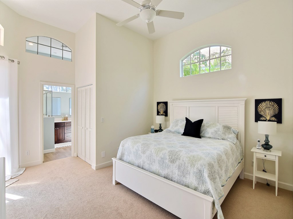 8785 Lakeside Boulevard Vero Beach, FL 32963 - Photo 13 of 36 a bedroom with a bed and a chandelier